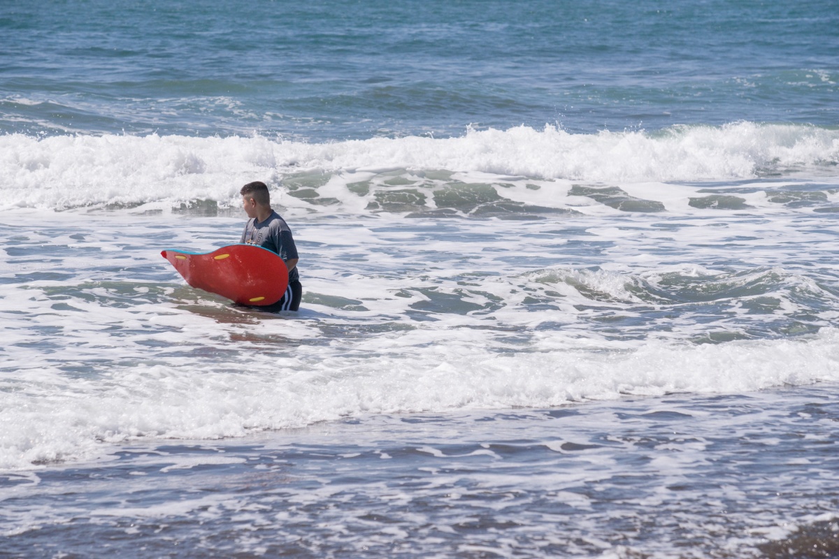 Boy with boogie board waiting in water for a wave