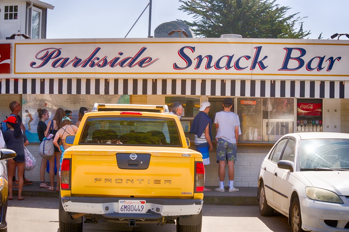 People waiting in line in front of a cafe named "parkside snack bar"